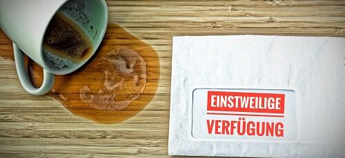 Einstweilige Verfügung neben umgefallener Kaffeetasse