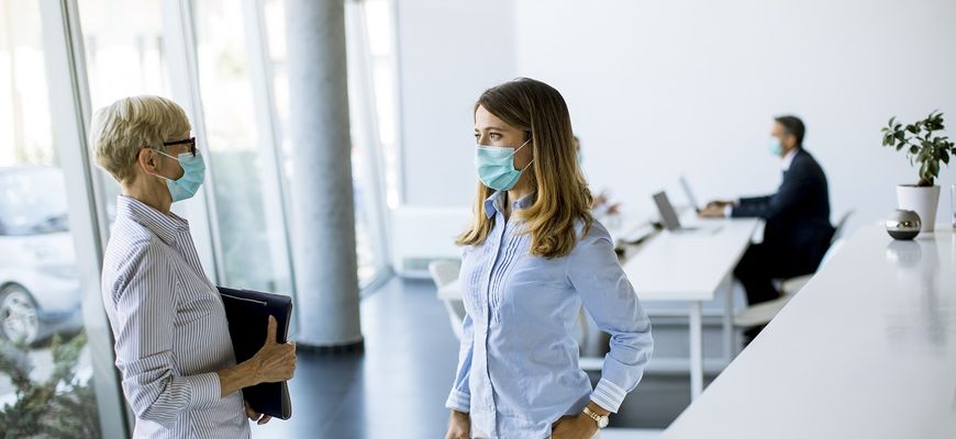 Frauen tragen Masken im Büro zum Schutz vor Corona
