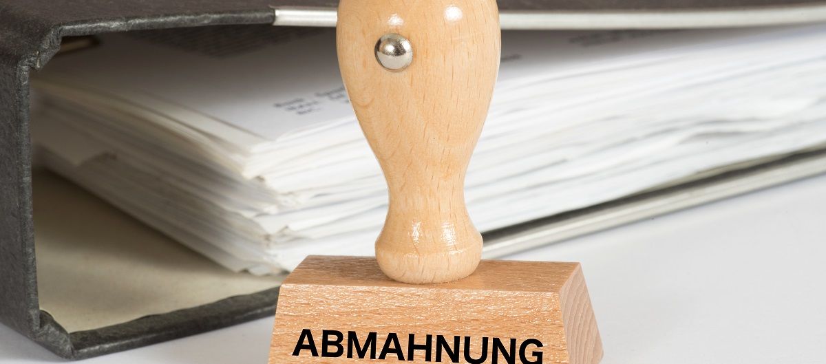 Stempel mit Abmahnung Aufschrift steht vor einem Ordner
