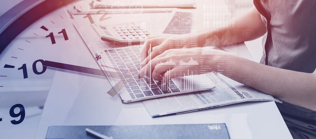 Arbeit am Computer mit Uhr im Hintergrund