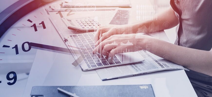 Arbeit am Computer mit Uhr im Hintergrund