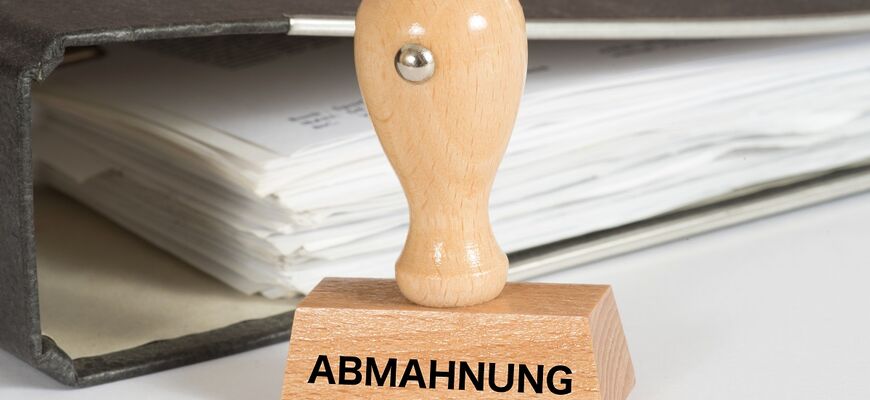 Stempel mit Abmahnung Aufschrift steht vor einem Ordner